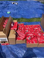 Several open cardboard boxes and loose red sealed bags of safety glasses displayed on a table
