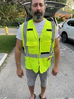 Front view of neon yellow Milwaukee safety vest worn by person, showing zipper front, multiple pockets, padded collar, and reflective striping.