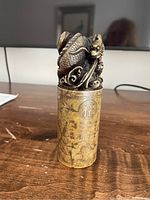 Front view of carved stone seal stamp on wooden surface featuring dragon carved top and engraved characters on side.