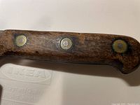 Close-up of wooden handle showing metal rivets and aged wood texture