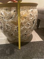 Front view of white ceramic planter with gold-painted rim and cranes design; measuring tape shows approx. 18″ height.