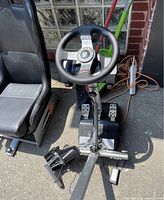 Gaming cockpit assembled with seat, steering wheel base and pedal set on concrete floor