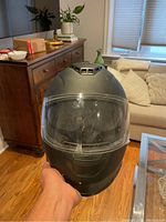 Front view of matte black full-face motorcycle helmet with clear shield and ventilation on top.