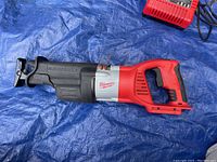 Side view of the Milwaukee M18 FUEL V28 18V Brushless Cordless Reciprocating Saw (tool only) showing red and black grip and blade clamp area.