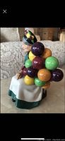 Side view of Royal Doulton Balloon Seller figurine showing colorful balloons attached to seated woman