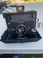 Front view of the Polaroid Pro Pack instant camera showing lens, focus dial, built-in flash attachment, and pop-up viewfinder.
