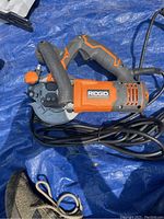 Top view of Rigid circular saw showing the handle, cord and blade guard on blue tarp.