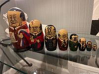 Photo showing all 8 nesting dolls lined up front side with painted faces and political attire.