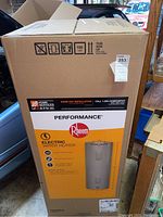 Front of sealed cardboard box showing Rheem Performance electric water heater graphics and capacity icons.
