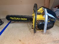 Side view of the yellow McCullough MAC 110 chainsaw showing the chain bar and handle frame.
