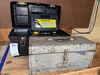 Metal tool box and plastic Stanley tool box side by side on wooden surface
