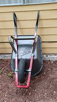 Front view of wheelbarrow showing single tire and red frame with black handles