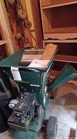 Side view of green steel hopper, discharge chute, wheels and engine