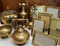 Brass items grouped including engraved teapot, lidded container, vase, bowl, candle holders, and solid brass picture frames of various sizes