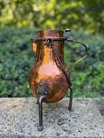 Front angled view of the copper coffee pot showing the hammered copper body, cast metal legs, and handle.