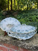 Photo showing three antique serving dishes by J & G Meakin with teal floral and gold trim decoration arranged outdoors on a stone surface.