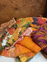 Stack of groovy vintage fabrics in various floral and psychedelic prints in warm colors.