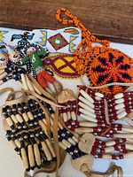 Close-up photo of the assortment showing colorful hand-beaded neck and wrist accessories, bone/chip bead rattles, and decorative pieces.