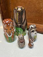 Five wood nesting dolls painted as animals: moose, deer, raccoon, porcupine, chipmunk.