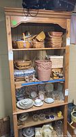 Front view of the wooden bookcase filled with baskets, dishes, and glassware to illustrate size and shelf space.