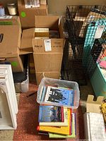 Wide shot showing several boxes and bins containing books and documents on a basement floor.