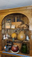 Wide view of wood shelving with figurines, large pears, baskets and glass items