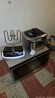 Panasonic microwave, black with digital control panel, and Farberware deep fryer with stainless steel body and transparent lid