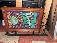 Full view of British pub sign showing colorful party advertisement with wooden frame and black metal base.
