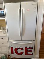 Exterior front view: white French doors and bottom freezer drawer with ‘ICE’ decal