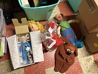 Overview photo showing all items in the lot including clown doll, boxed "Catch Me If You Can" doll, Tickle Me Elmo in packaging, and rabbit puppet