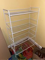 Front angle view of the white wire folding storage shelf showing four tiers.