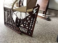 Pair of antique carved wooden corbels placed on floor showing full view of front and side details with chairs in background.