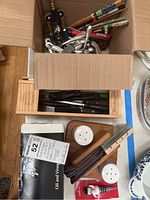 Photo of box containing chopsticks, cutlery, bottle openers, salt and pepper shakers, cruet set.