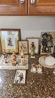Full arrangement of figurines and wall art displayed on a granite countertop with wood cabinets in background.