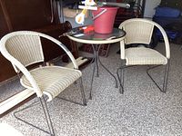 Photo showing the full patio set including two woven chairs and the glass top table.