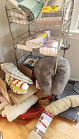 View of chrome metal rolling cart with items on and around it including bath mats, neck pillows, and packaged briefs.