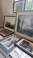 Nine pieces of assorted wall art leaning against a wall and window. Includes framed and matted landscapes and photo prints with varied frame colors and sizes.