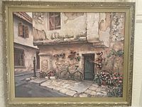 Photo of large framed painting featuring a street scene with a bicycle, stone pavement, flower pots, and old textured building walls.