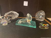 Five assorted Swedish crystal and glass figurines arranged on a table with a black background and a lot number label.