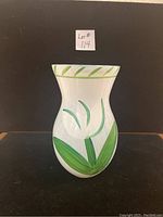 Frontal view of the Kosta Boda vase showing green leaf and stripe hand-painted designs on translucent white textured glass.