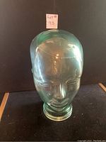 Front view of a clear glass head sculpture showing facial features and overall shape.