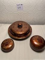Three pieces of Japanese lacquerware with tortoise design: a lidded divided tray and two round lidded containers, all showing wear.