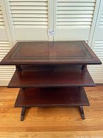 Front view of the three-tier Deilcraft library table showing the wood shelves and claw feet.