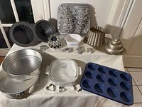 Wide view showing full assortment of bakeware including tart pans, molds, Pyrex dish, cookie cutters and silicone cupcake tray.