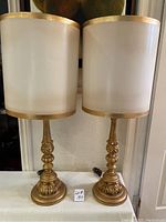 Pair of vintage Italian carved wooden lamps with white fabric shades and gold trim shown side by side unlit.