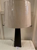 Taller Crate & Barrel lamp with new large beige fabric drum shade showing subtle texture and matte black tapered rectangular base.