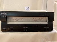 Front view of Yamaha A100 amplifier powered off showing VU meters, power switch, headphone jack, output level controls, and clip indicators.