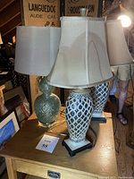 Three lamps on wooden table showing varying blue ceramic bases with fabric shades under dim light.