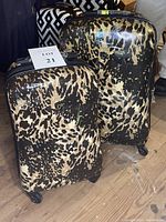 Both 28-inch and 21-inch brown animal print hard case suitcases side by side, showing their spinner wheels and telescoping handles.