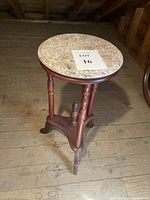Full view of the vintage round table with a marble top and mahogany wood base on wooden floor.